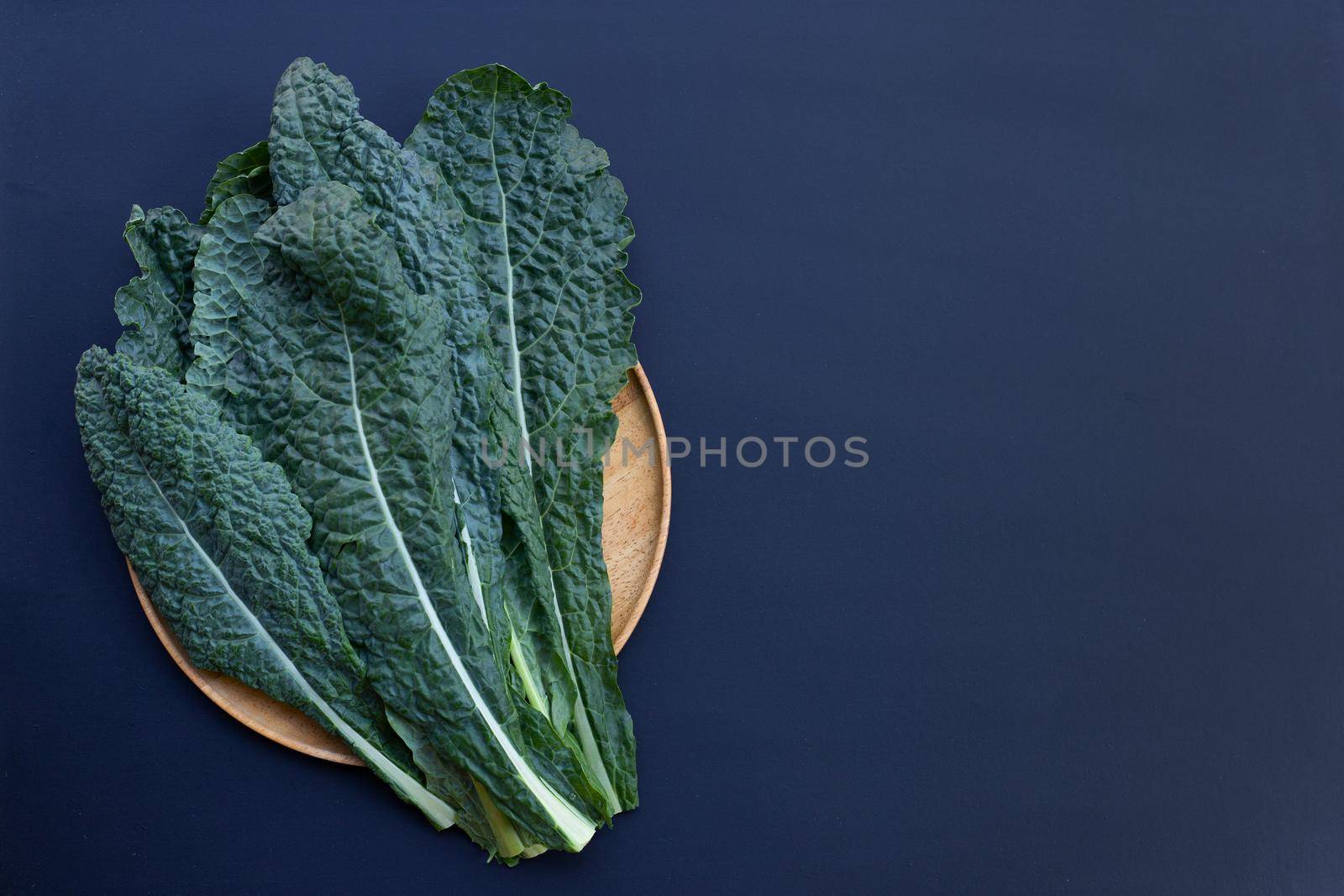 Fresh organic green kale leaves on dark background.