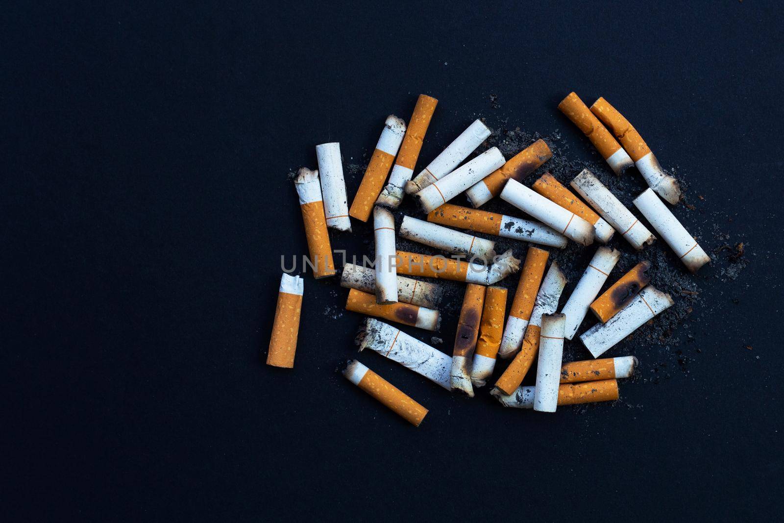 Dirty cigarette buds on black background.