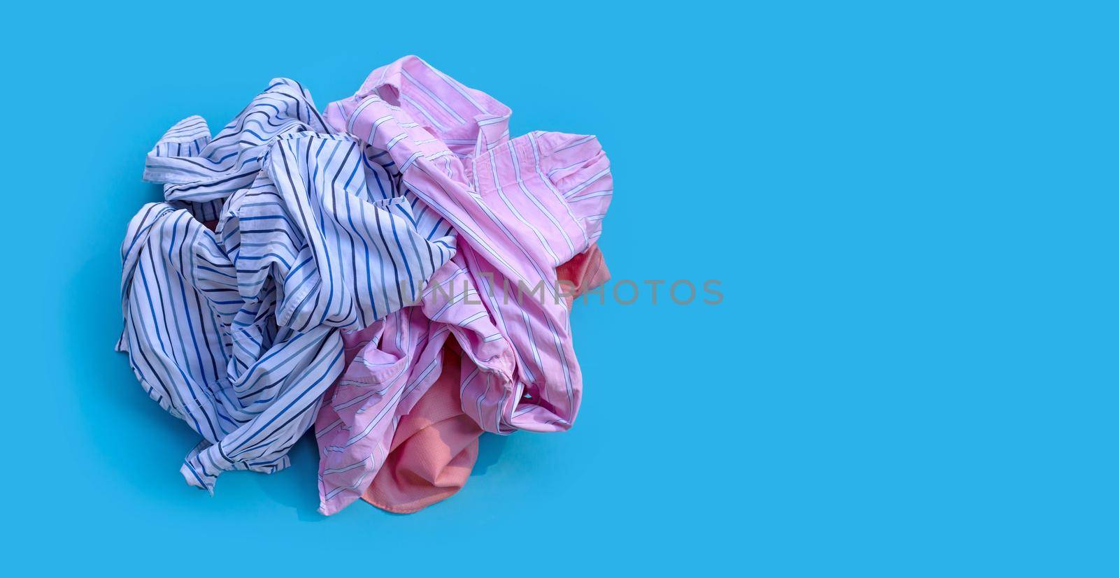 Pile of used clothes on blue background.