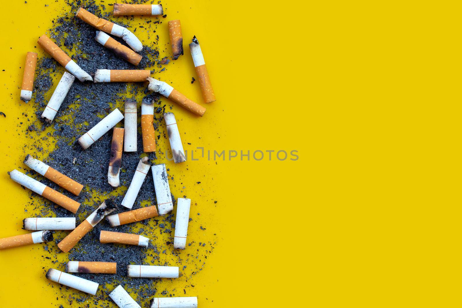 Cigarettes buds with ashtray on yellow background. 