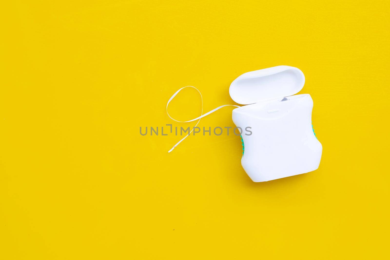 Dental floss on yellow background. Copy space