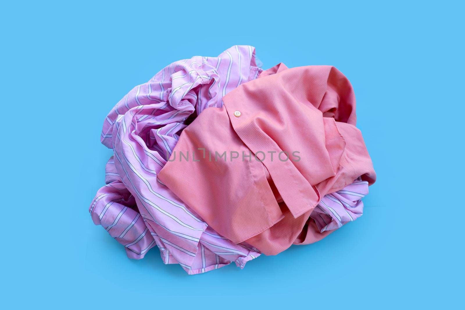Pile of used clothes on blue background. 