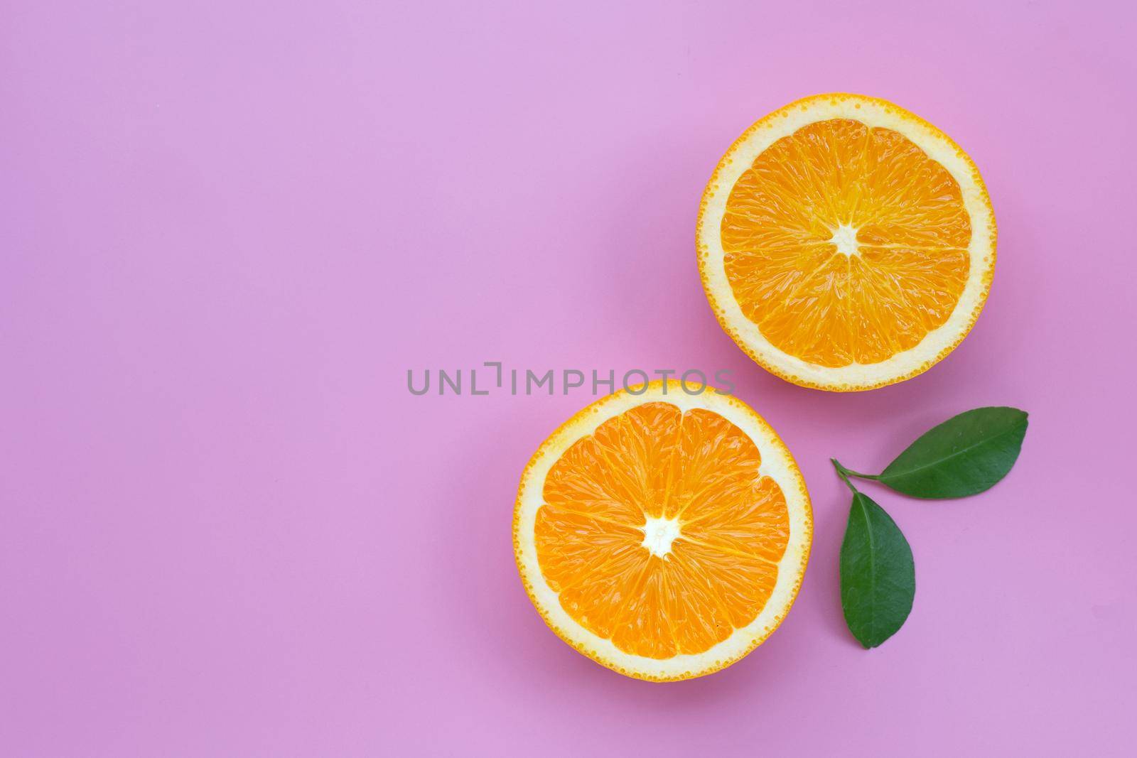 High vitamin C, Juicy and sweet. Fresh orange fruit with green leaves on pink background.