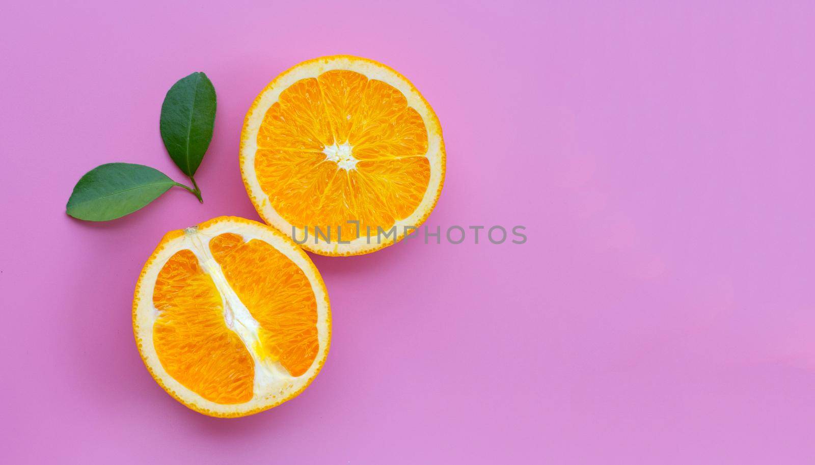 High vitamin C, Juicy and sweet. Fresh orange fruit with green leaves on pink background.