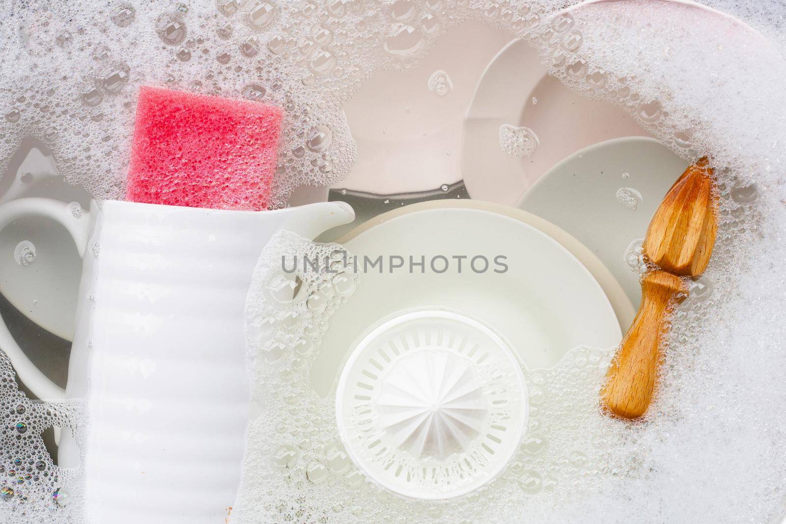 Washing dishes, Close up of utensils soaking in kitchen sink.