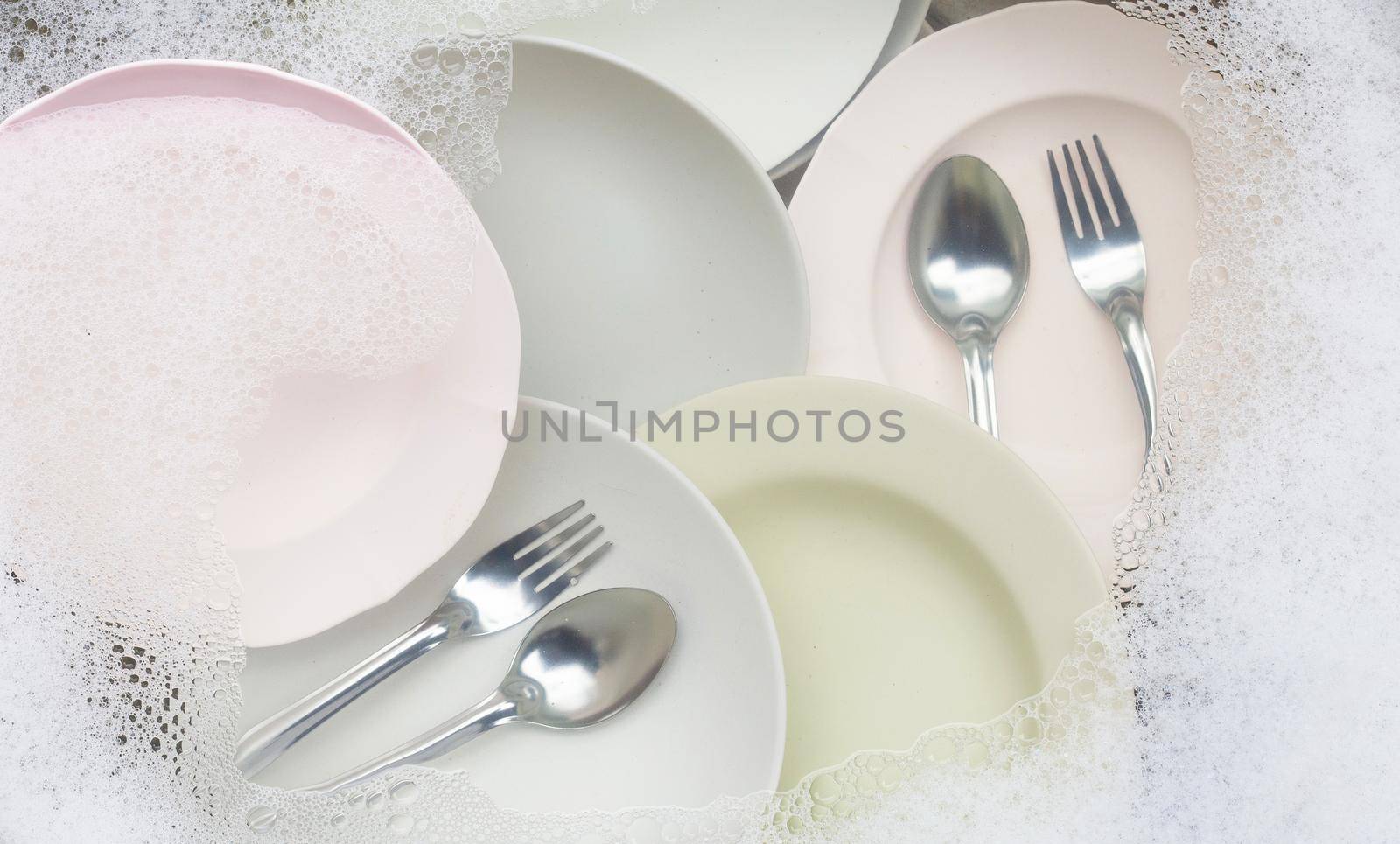 Washing dishes, Close up of utensils soaking in kitchen sink.