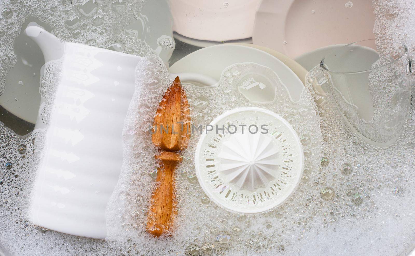 Washing dishes, Close up of utensils soaking in kitchen sink.