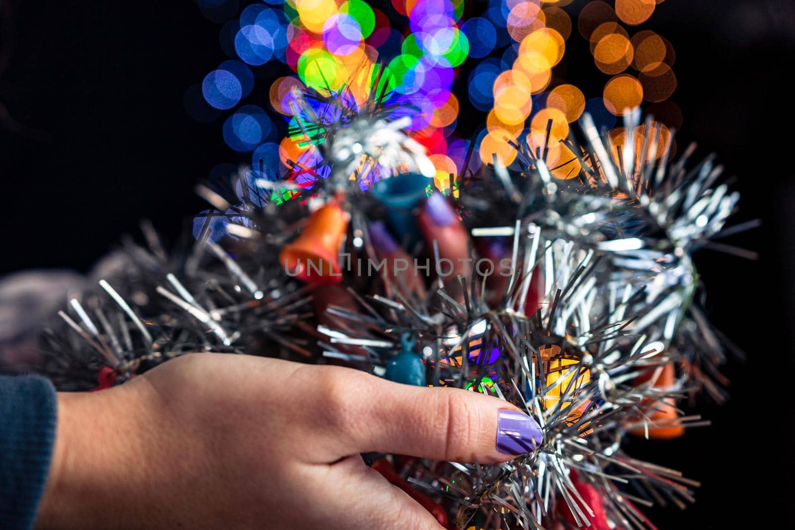 Holding Christmas garland decoration isolated on background with blurred lights. December season, Christmas composition.