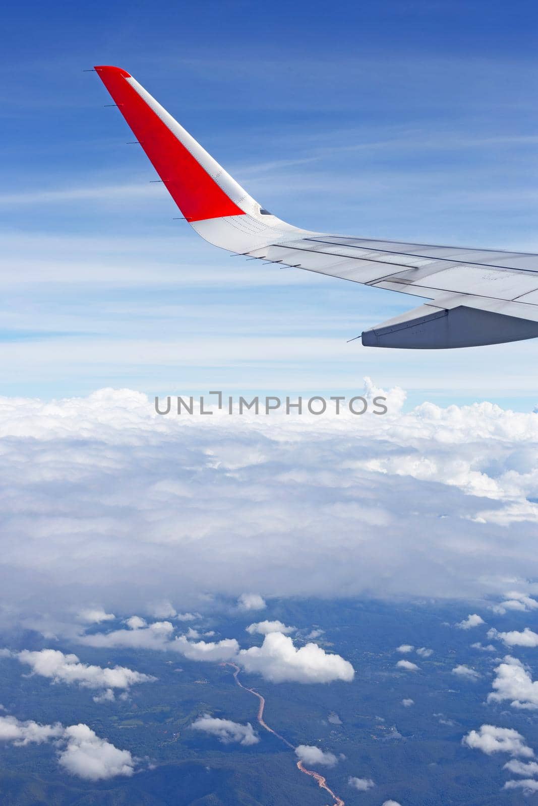 View of land, sky, cloud and wing of airplane from window by Bowonpat