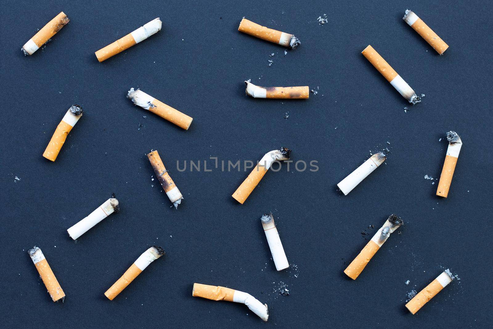 Dirty cigarette buds on black background.
