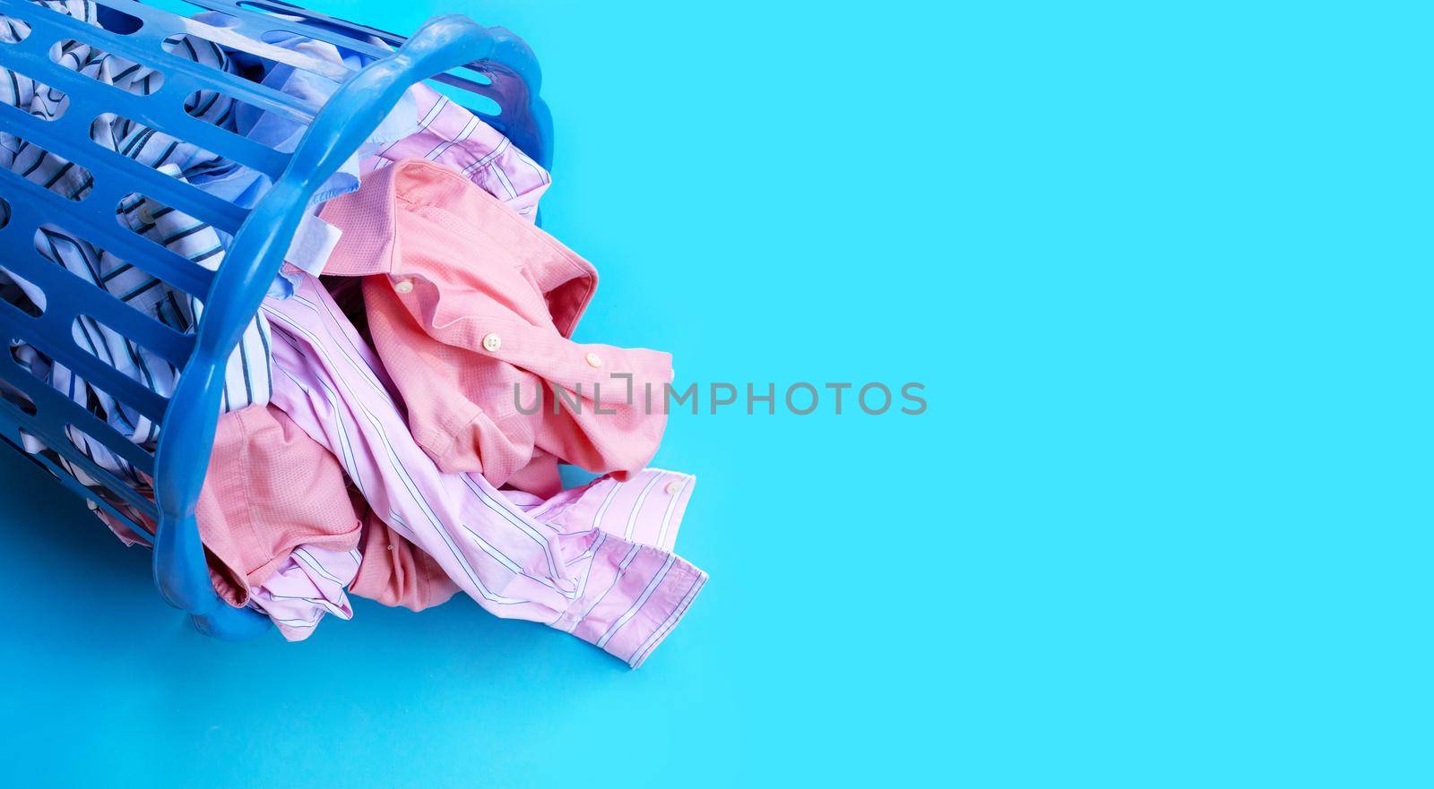  Clothes in a laundry basket on blue background. Copy space