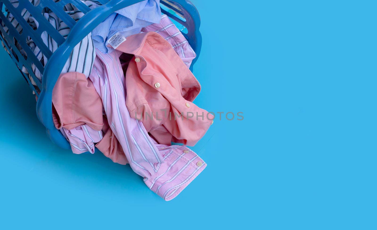 Clothes in plastic laundry basket on blue background. Laundry concept