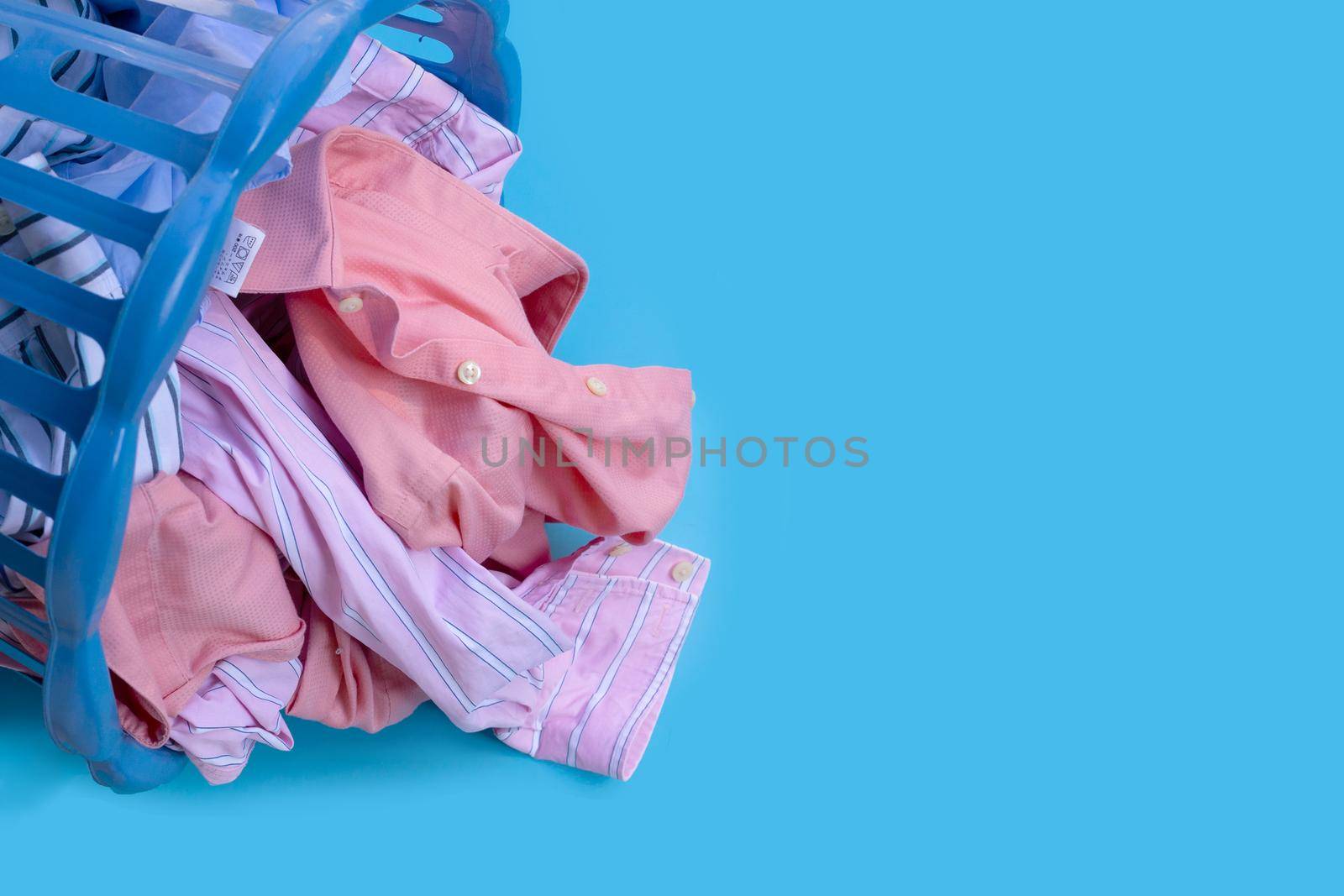 Clothes with a laundry basket on blue background. Copy space