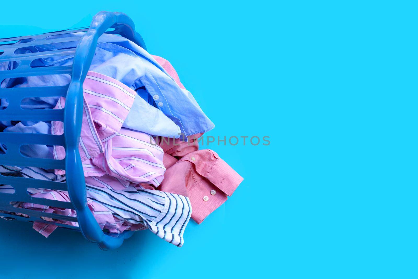 Clothes with a laundry basket on blue background. Copy space