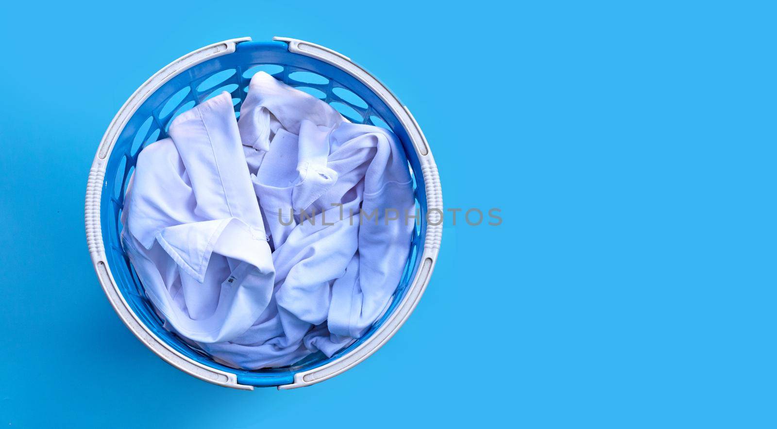 White clothes in a laundry basket on blue background.