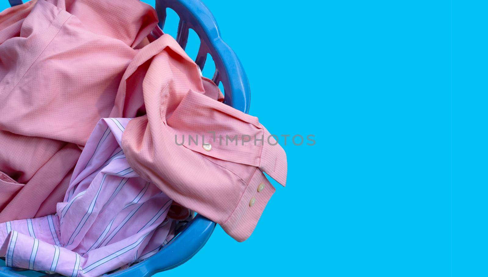 Clothes in a laundry basket on blue background. Copy space