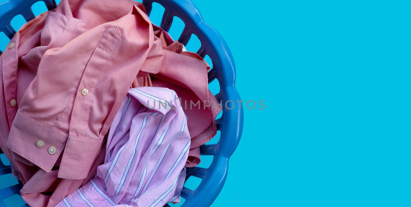 Clothes in a laundry basket on blue background. Copy space