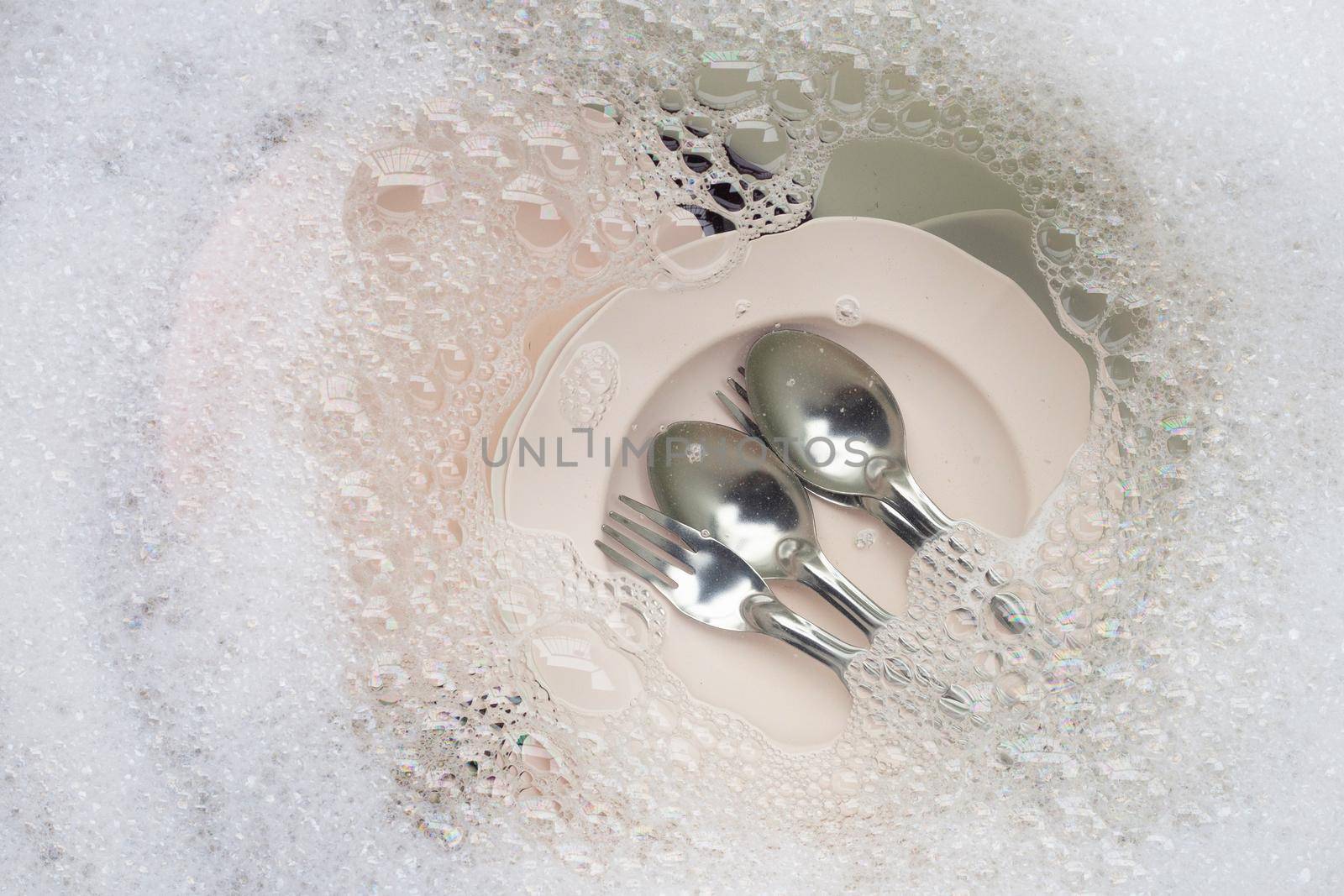 Washing dishes, Close up of utensils soaking in kitchen sink.