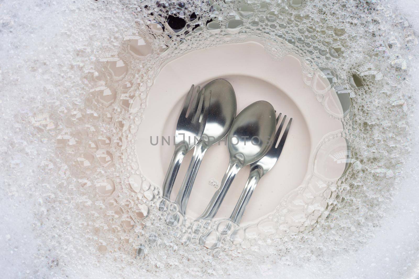 Washing dishes, Close up of utensils soaking in kitchen sink.
