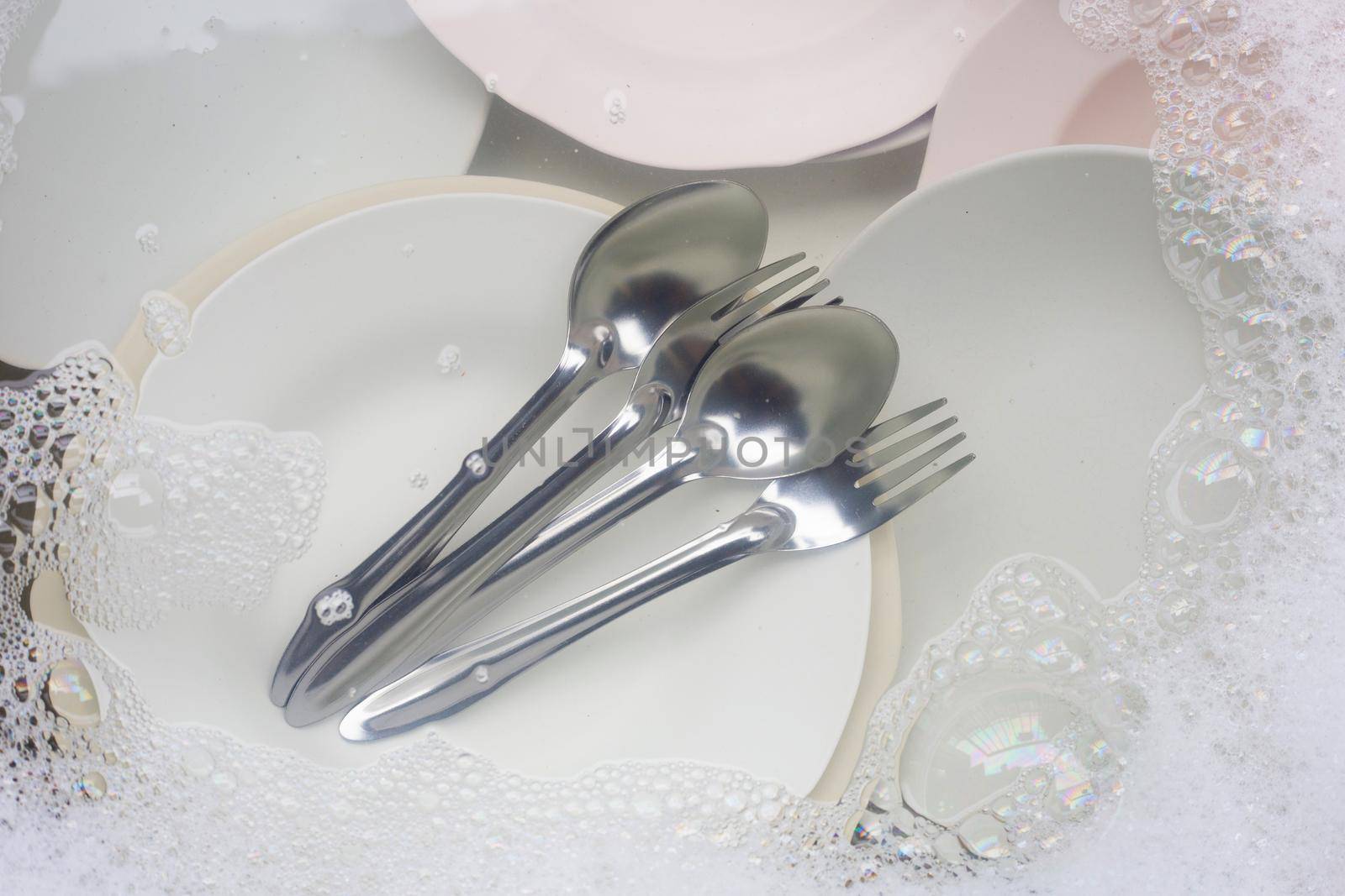 Washing dishes, Close up of utensils soaking in kitchen sink. by Bowonpat