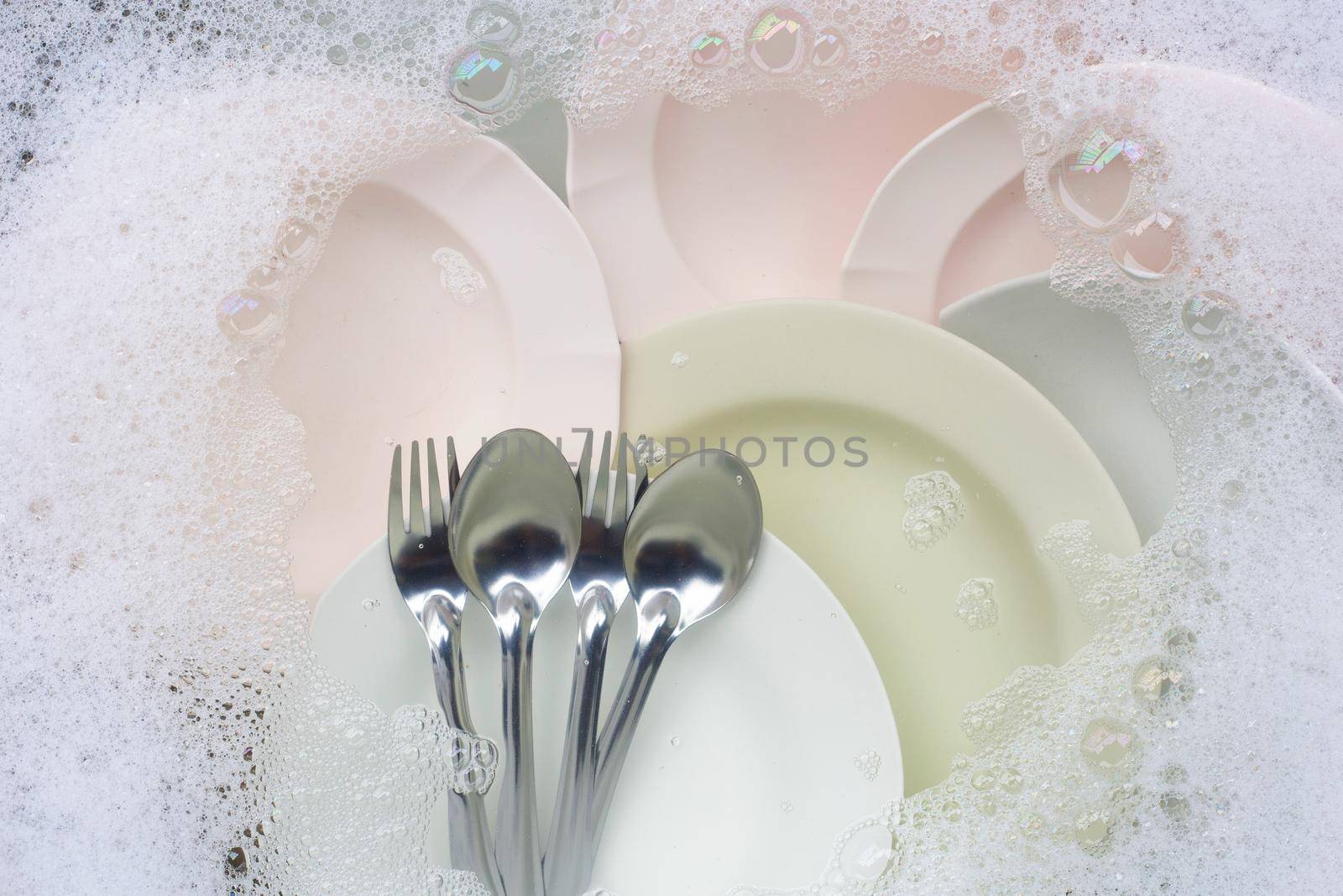 Washing dishes, Close up of utensils soaking in kitchen sink.