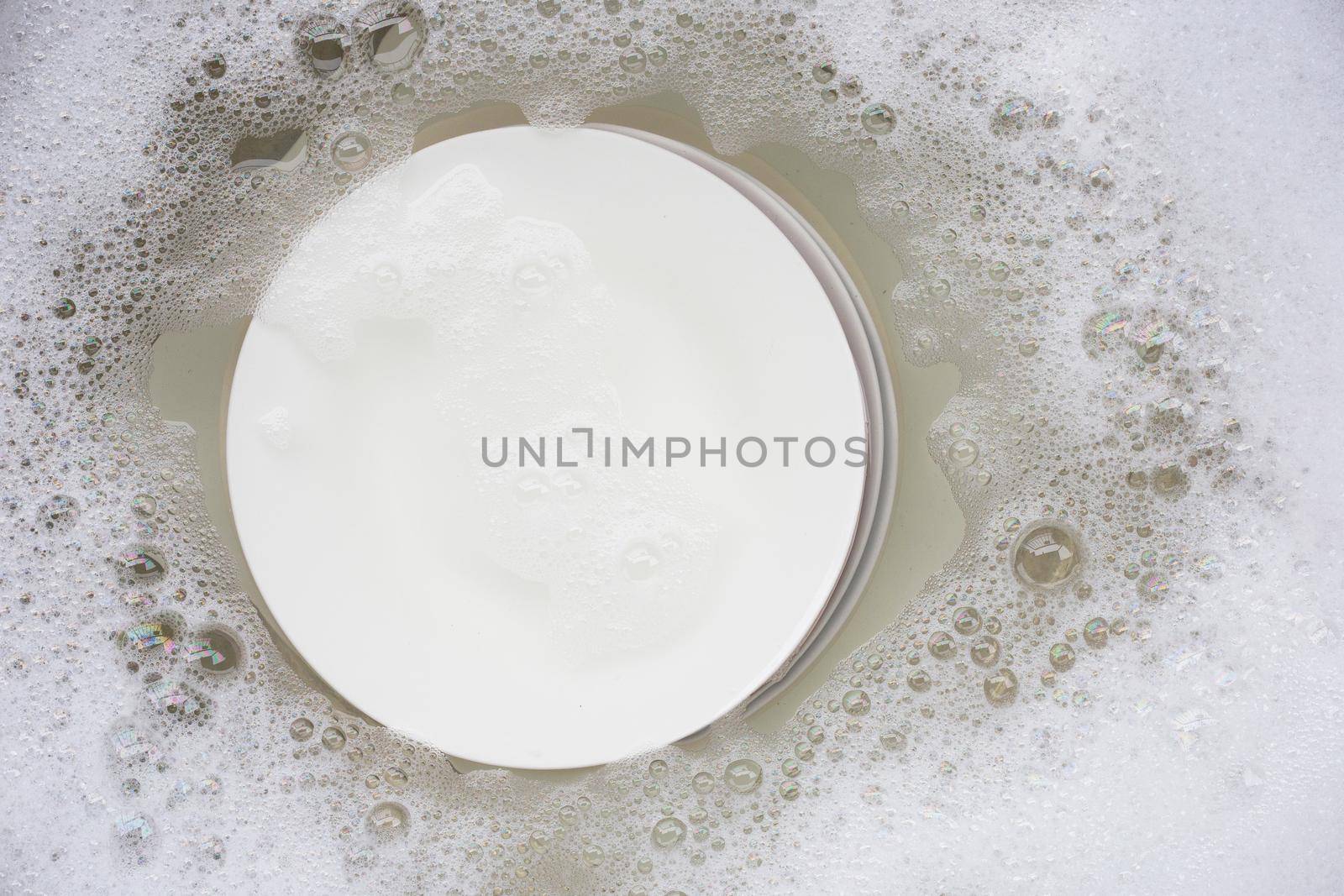 Washing dishes, Close up of utensils soaking in kitchen sink. by Bowonpat