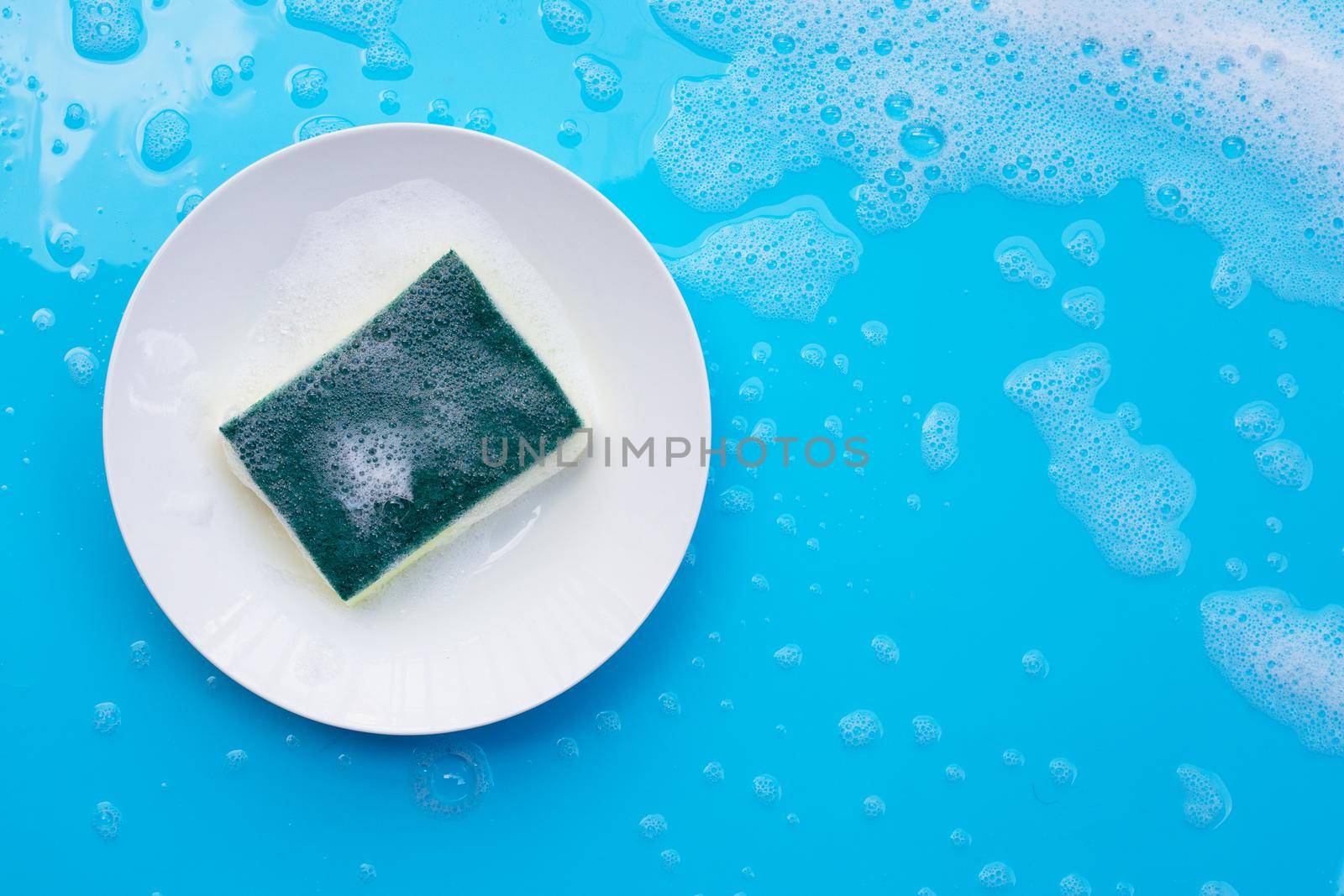 Washing dishes concept on wet blue background. Top view by Bowonpat