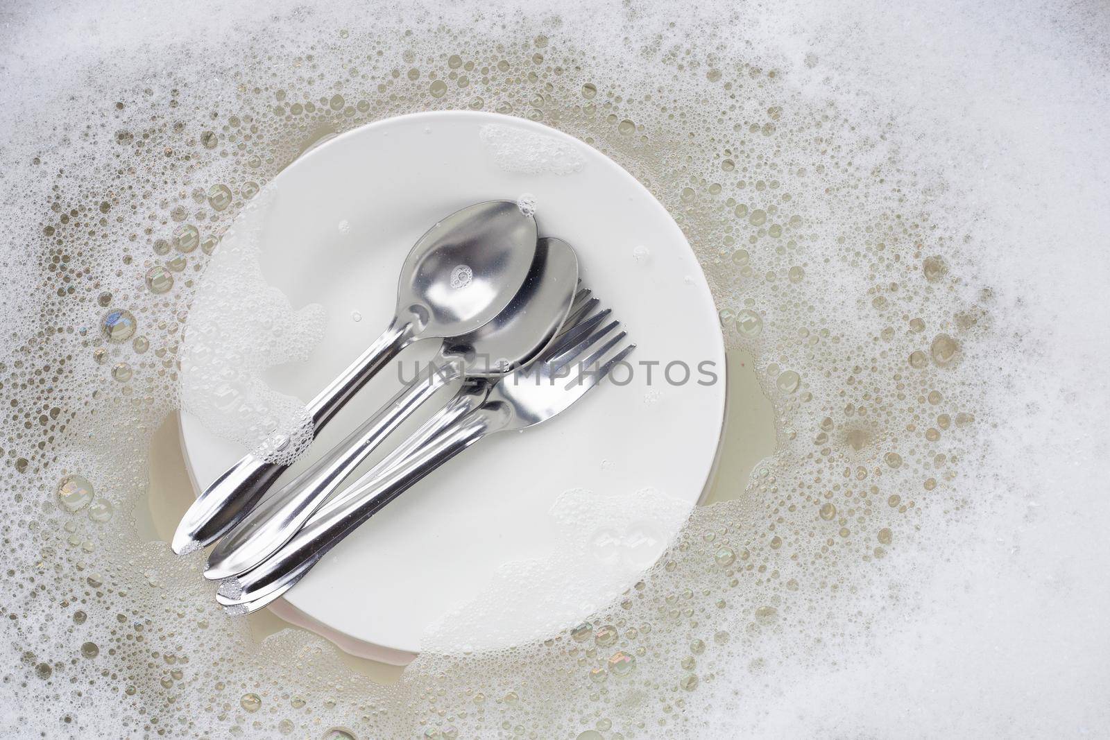 Washing dishes, Close up of utensils soaking in kitchen sink. by Bowonpat