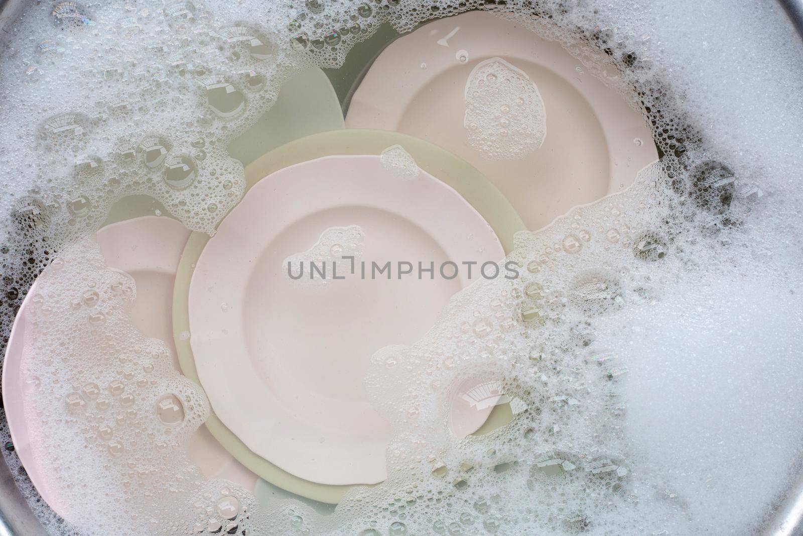 Washing dishes, Close up of utensils soaking in kitchen sink. by Bowonpat