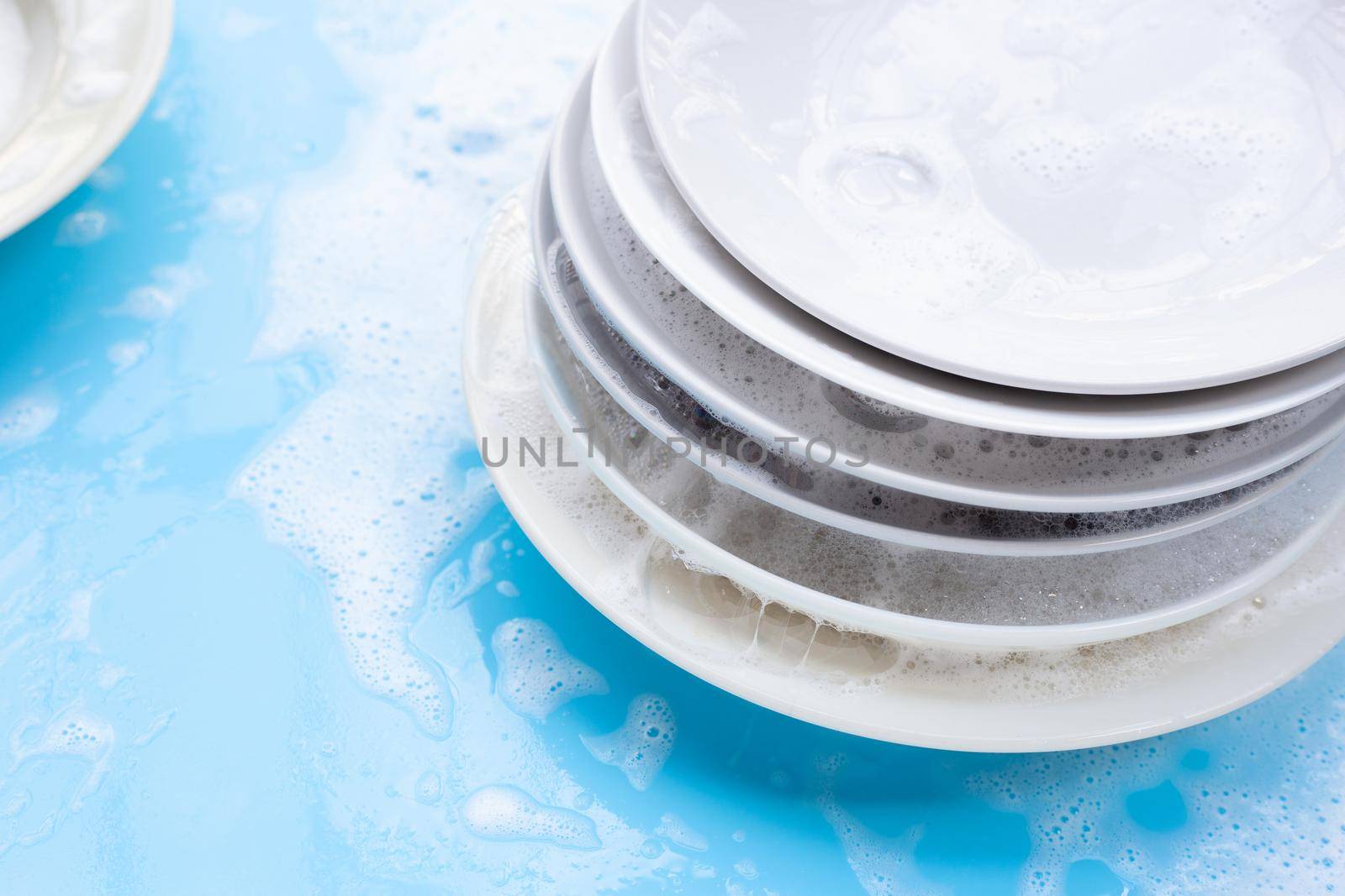 Washing dishes concept on wet blue background.