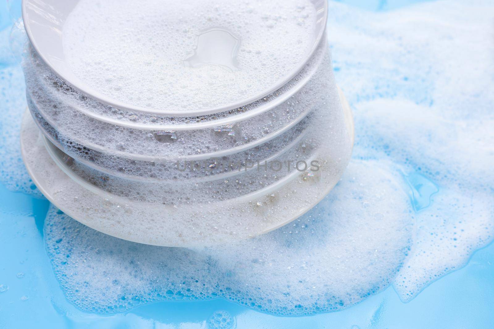 Washing dishes concept on wet blue background. by Bowonpat