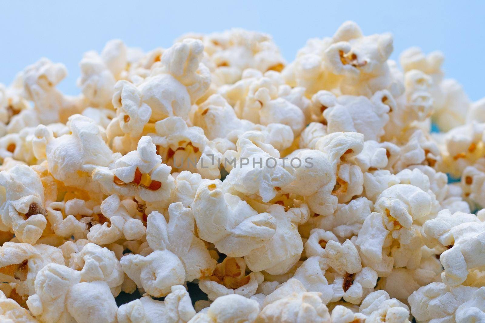 Popcorn on blue background. Copy space by Bowonpat