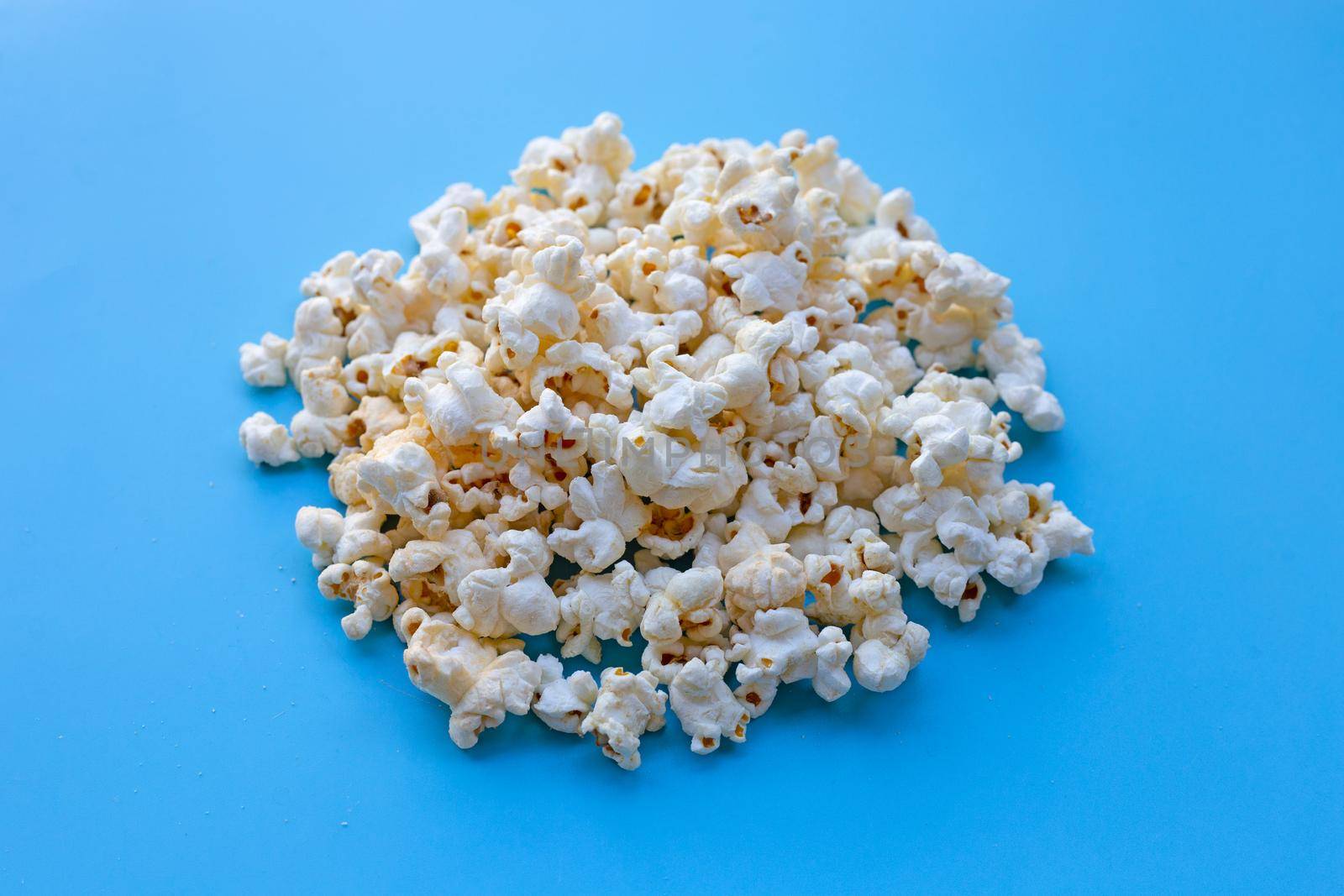 Popcorn on blue background. Copy space