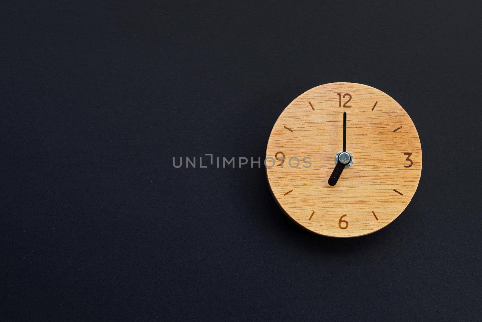 Wooden clock on dark background. Copy space