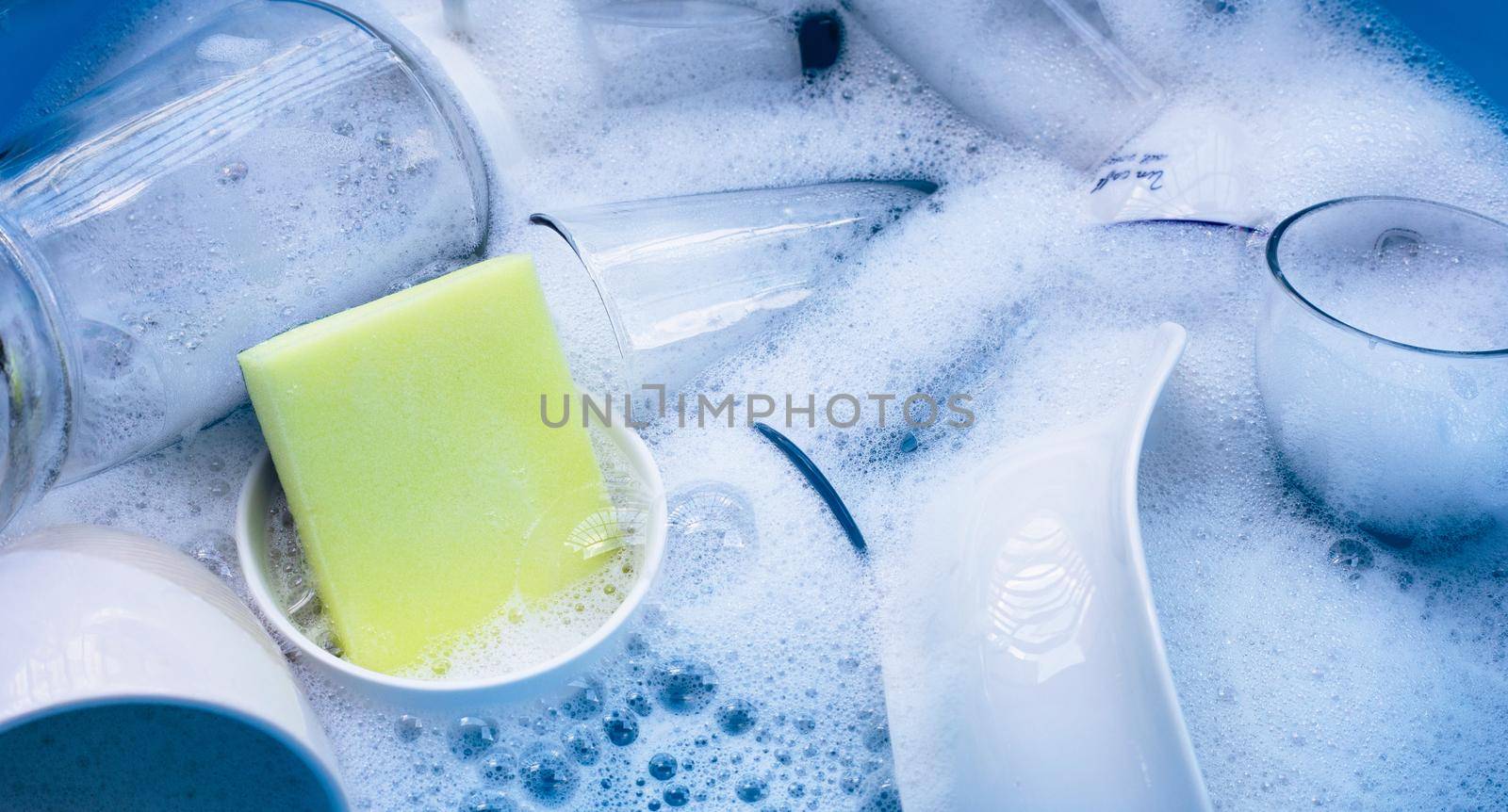 Washing used drinking glasses and cups with yellow sponge