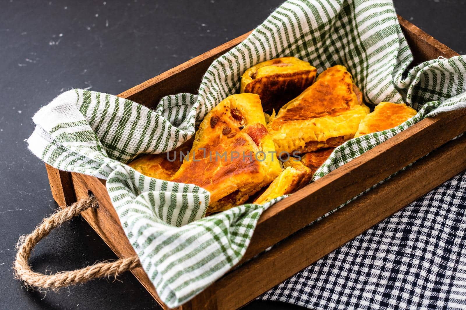 Freshly baked homemade ham and cheese puff pastry in a rustic crate.