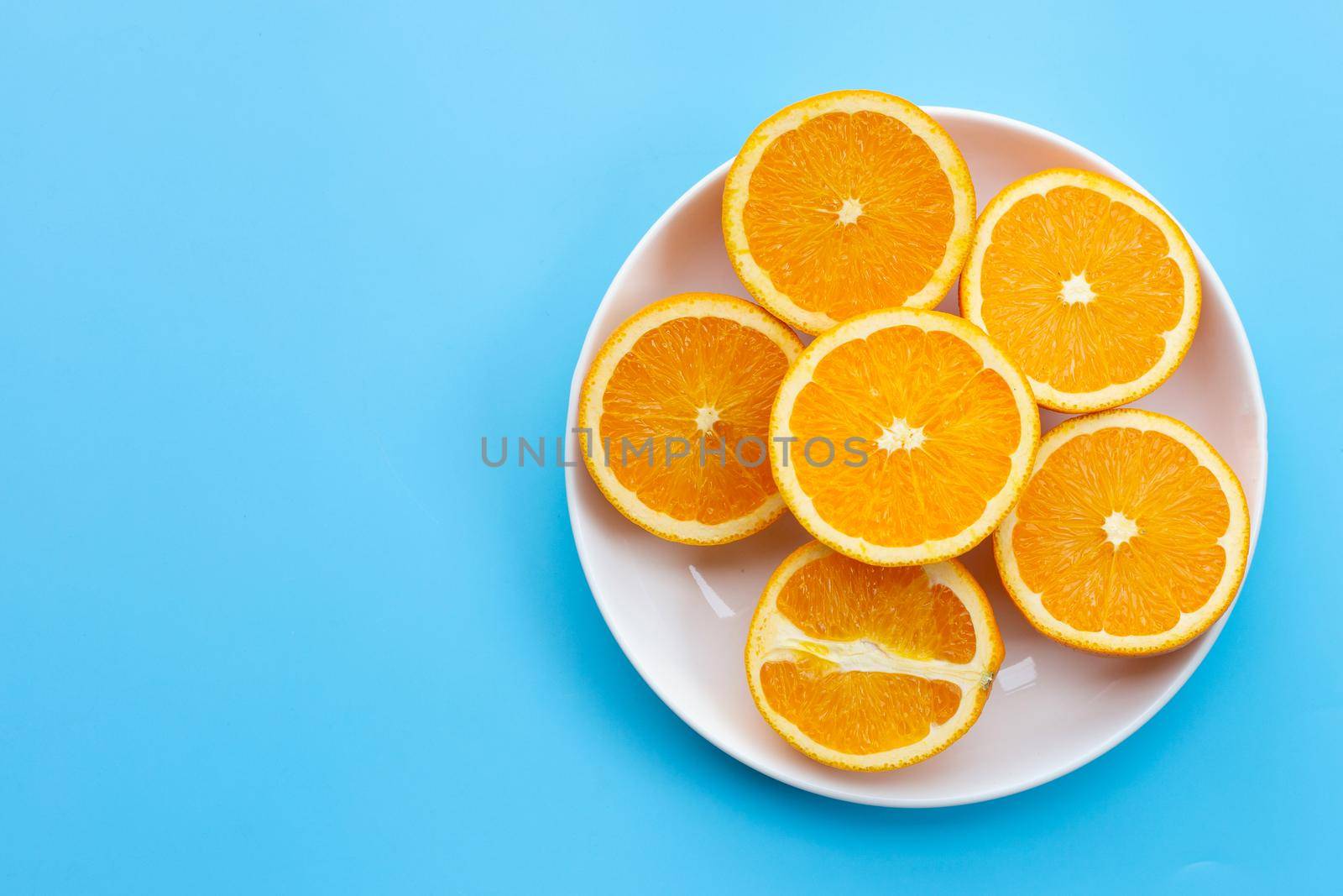 Sliced oranges on blue background. High vitamin C, Juicy and sweet. by Bowonpat