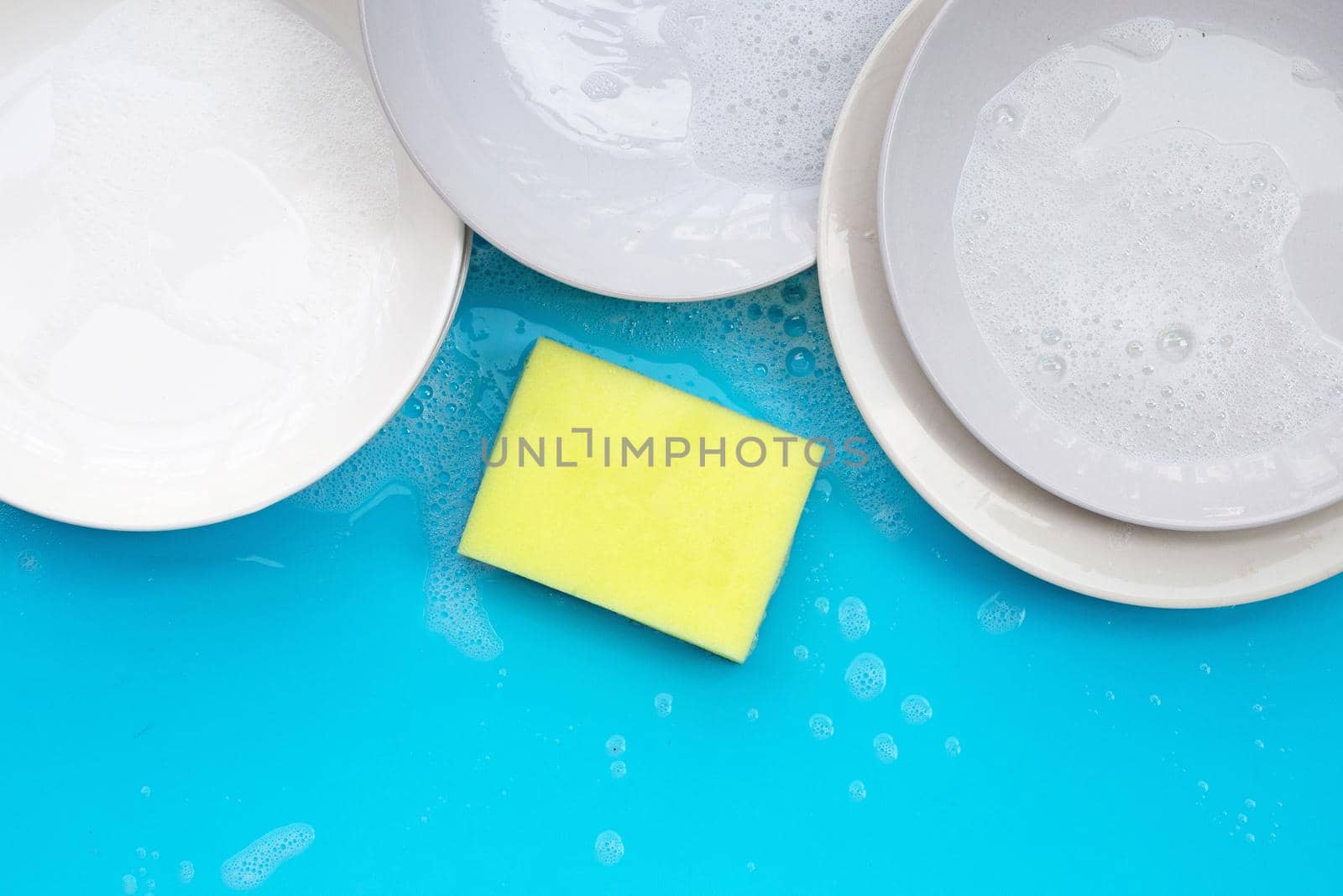 Washing dishes concept on wet blue background. Top view