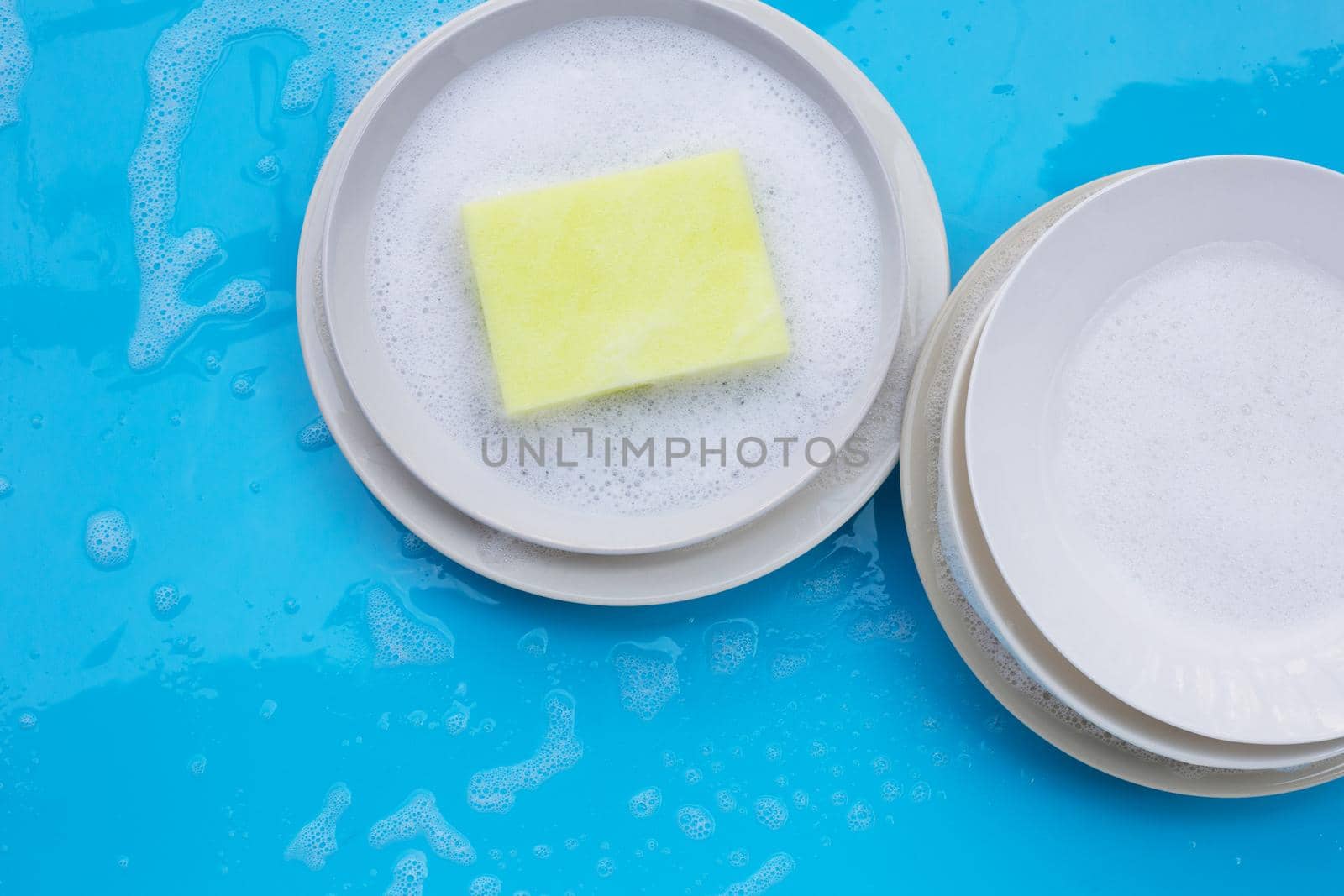 Washing dishes concept on wet blue background. Top view