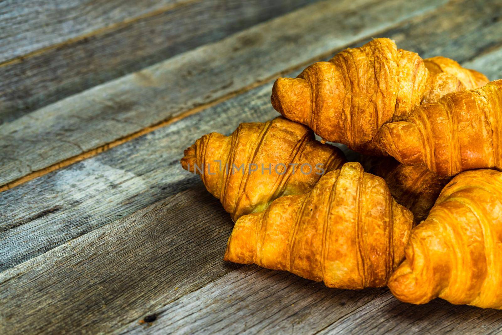 Delicious, fresh croissants isolated on wooden board. French breakfast concept.