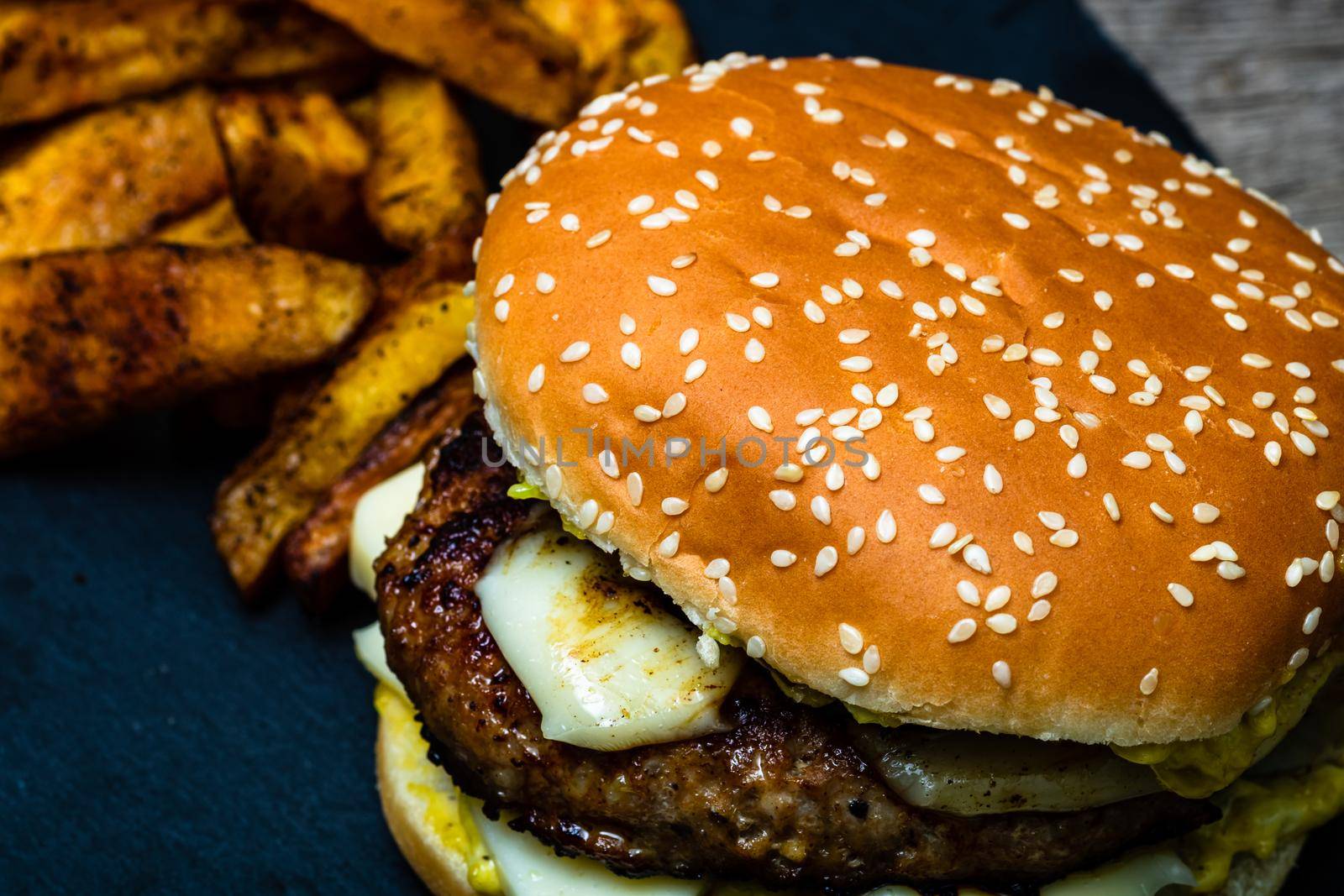 Homemade fresh tasty cheese burger and fried potatoes on a wooden table