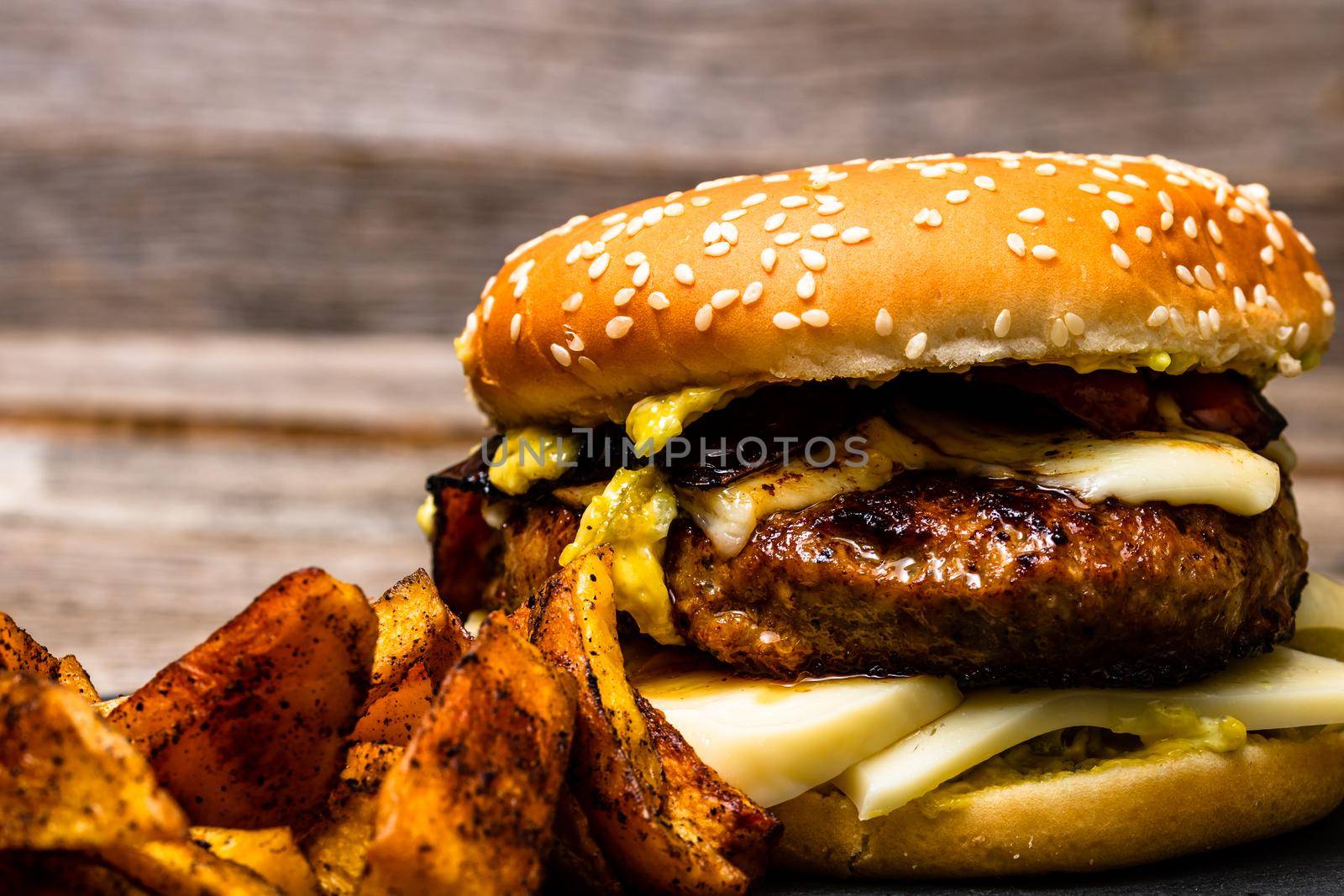 Homemade fresh tasty cheese burger and fried potatoes on a wooden table