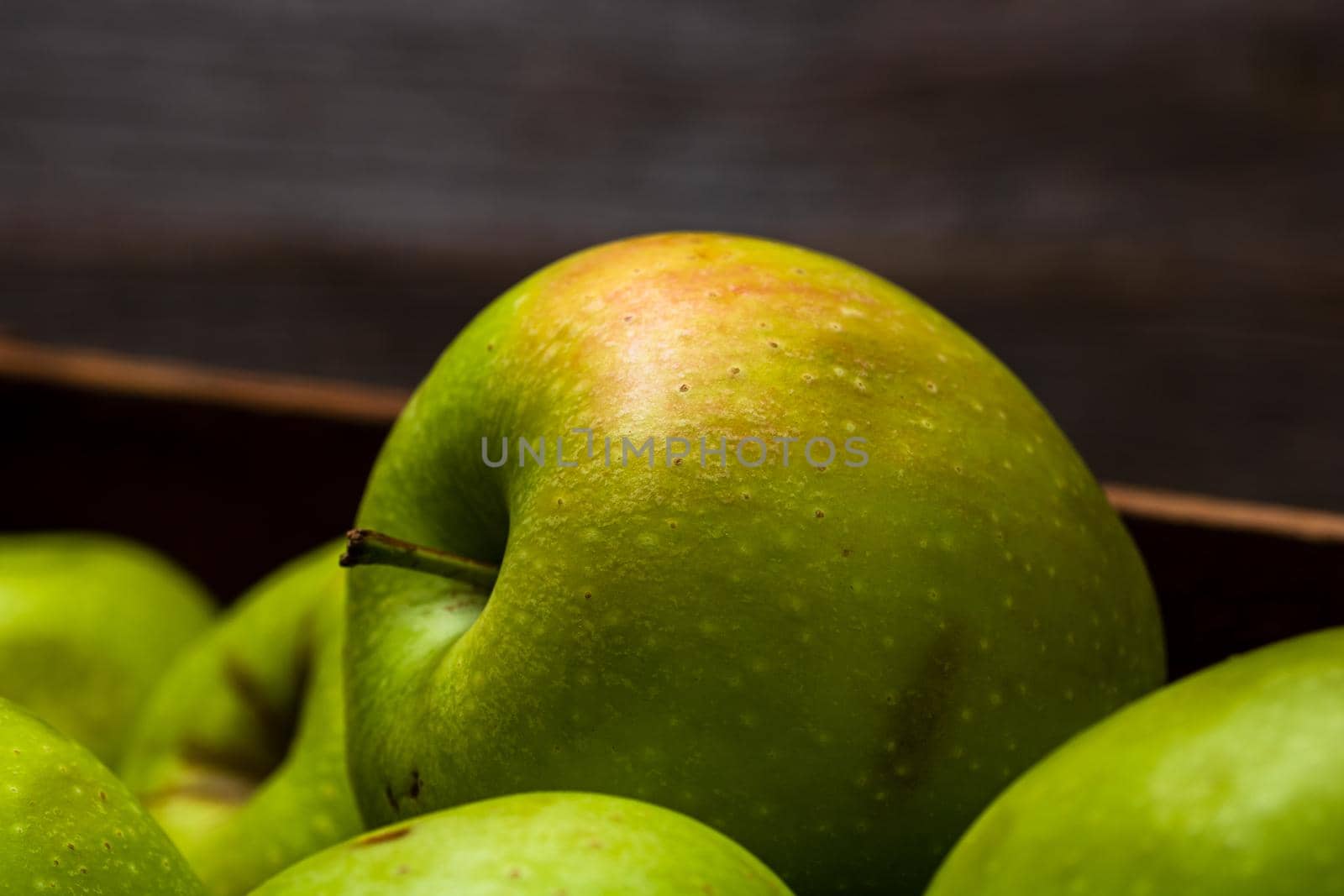 Wooden crate with ripe green apples on wooden table. by vladispas