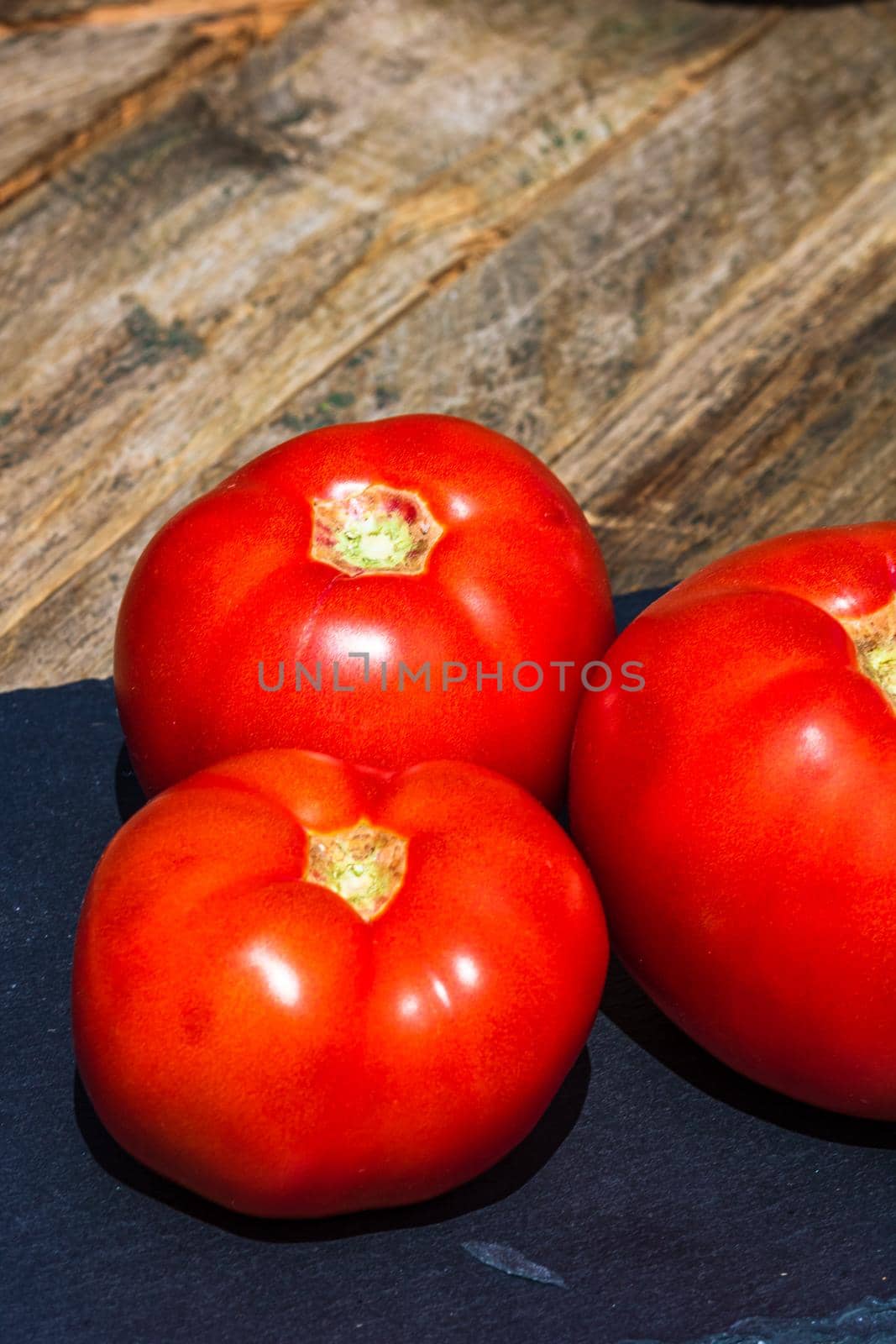 Close up of fresh ripe tomatoes isolated in a rustic composition, by vladispas