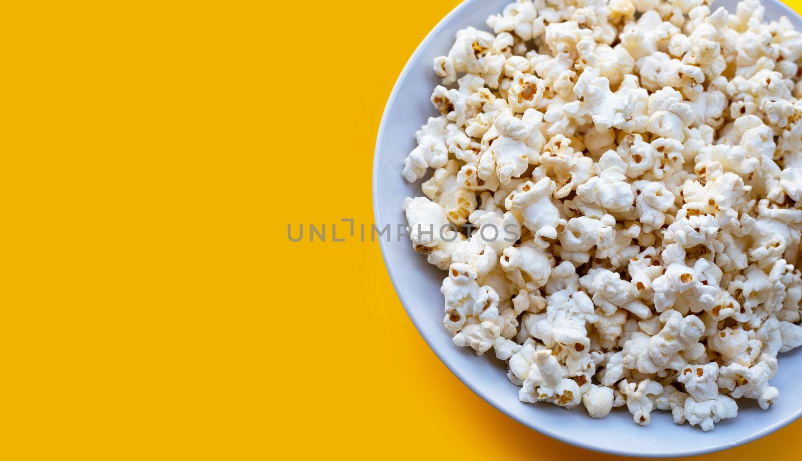 Popcorn on yellow background. Copy space by Bowonpat