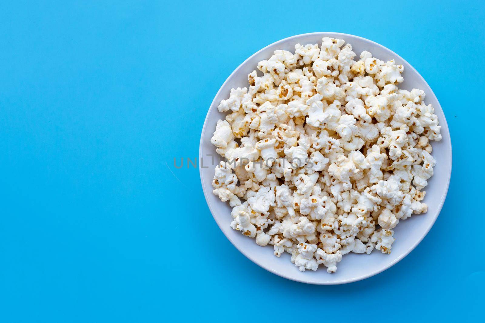 Popcorn on blue background. Copy space