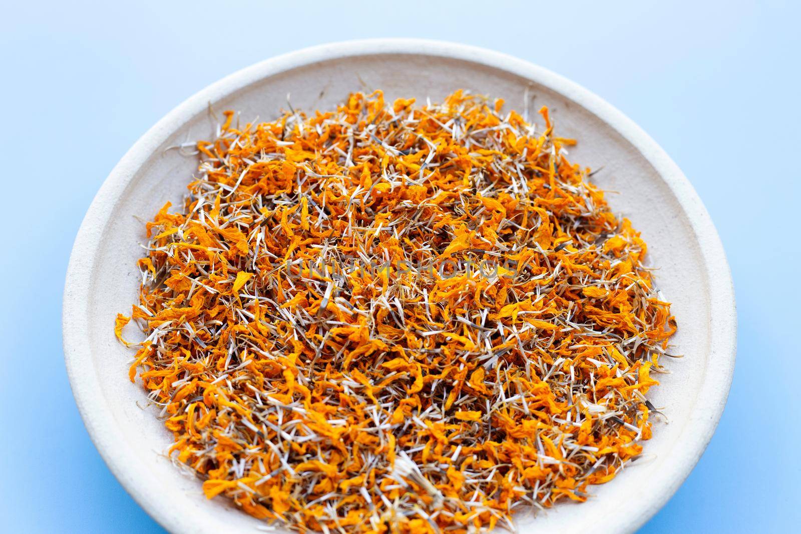 Dried marigold flower petals on blue background