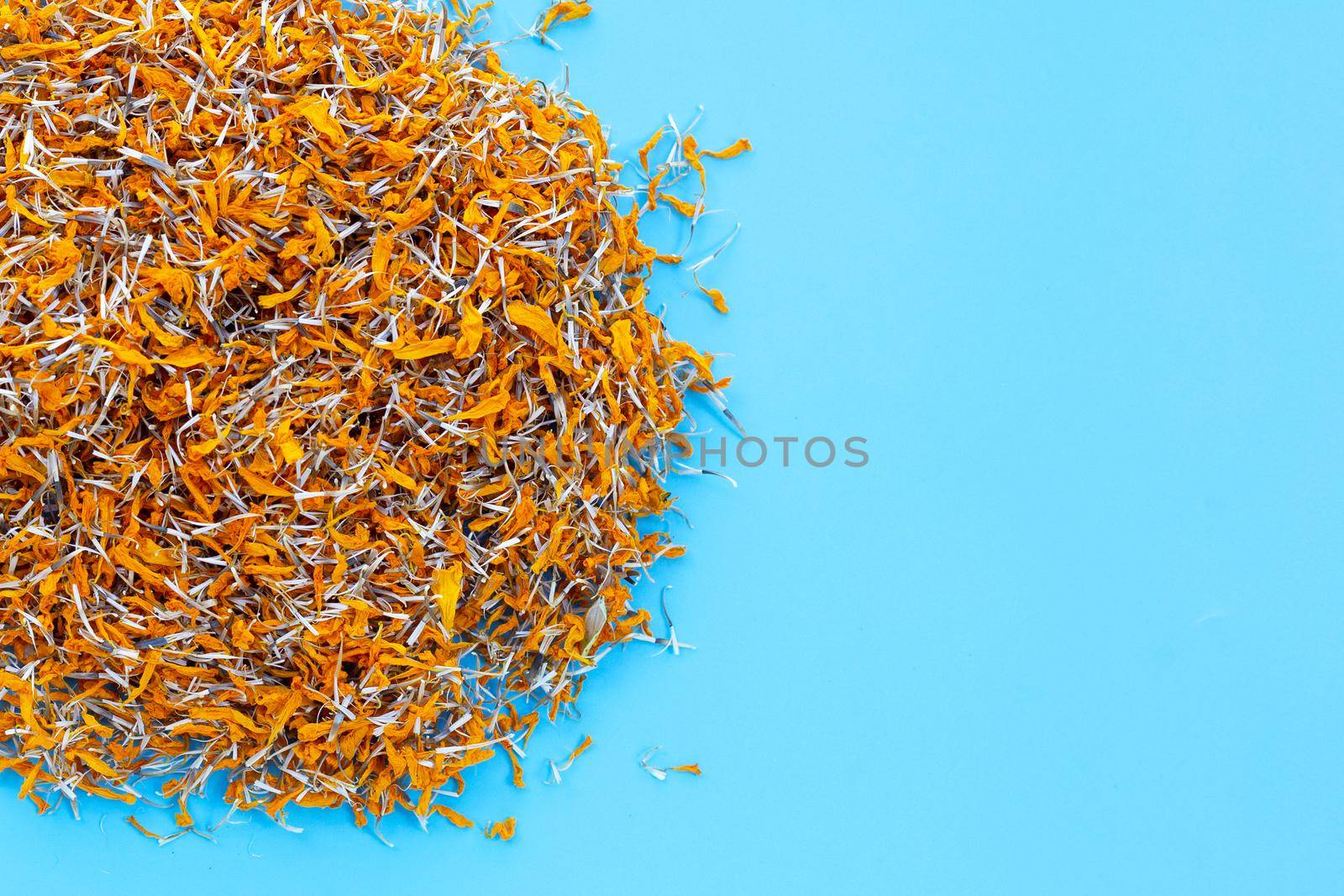 Dried marigold flower petals on blue background