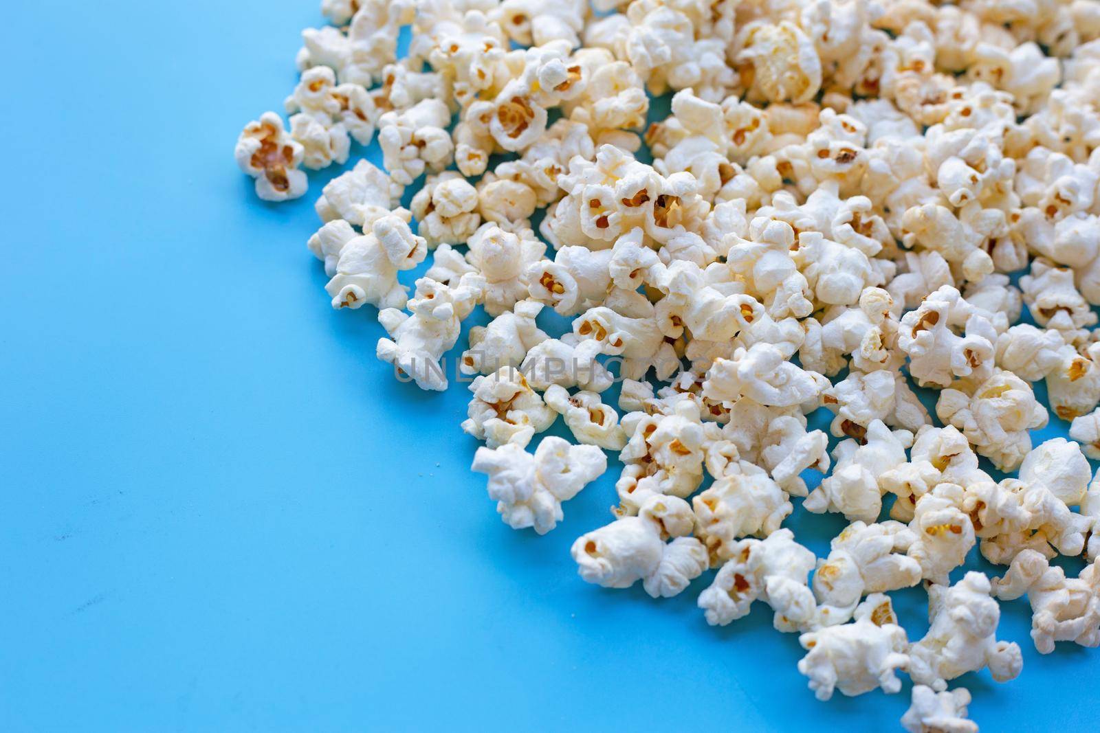 Popcorn on blue background. Copy space by Bowonpat