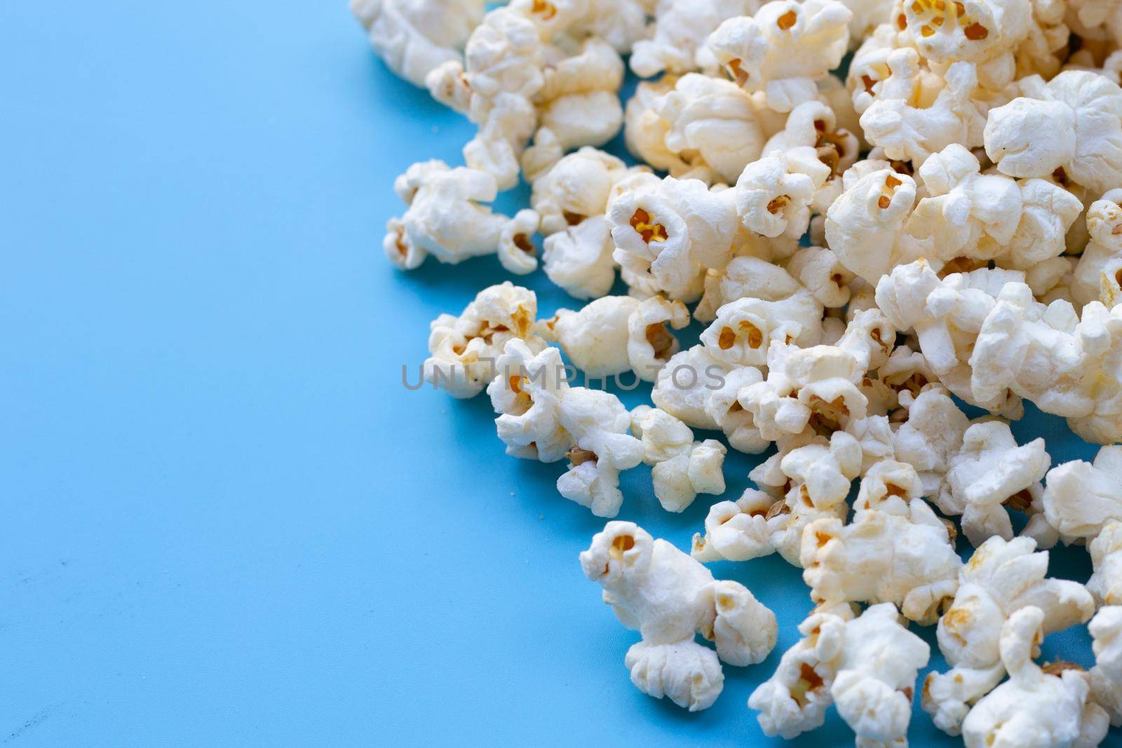 Popcorn on blue background. Copy space